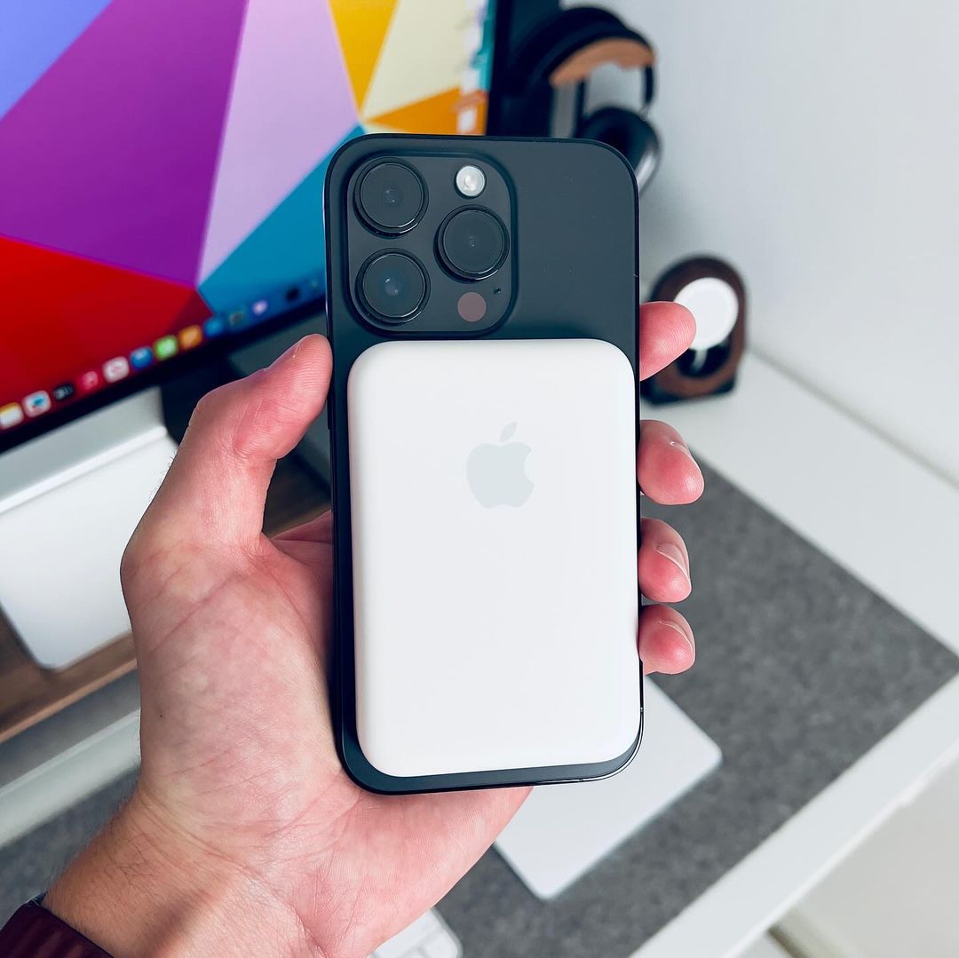 Person holding a smartphone with an Apple logo in front of a colorful screen