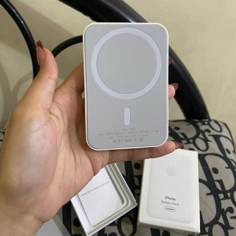 Hand holding a white portable battery pack with Apple branding