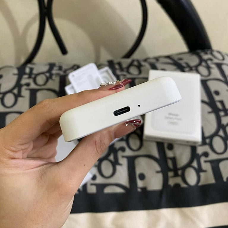 Hand holding a white electronic device with a blurred background