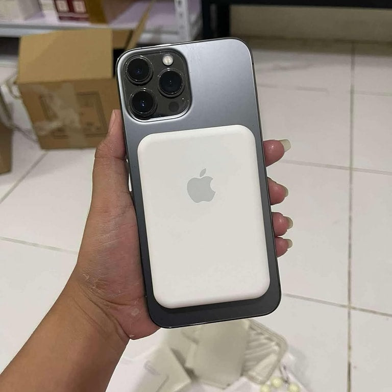 Hand holding a smartphone with a MagSafe case in an indoor setting